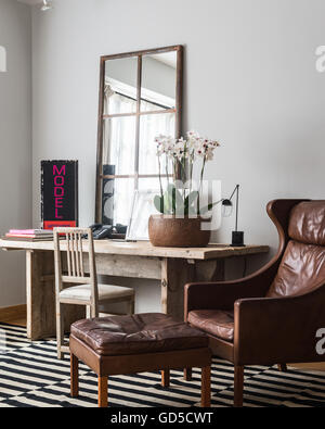 Pot en bois d'orchidées sur table rustique en bois dans la salle de séjour avec boiseries et miroirs wing retour fauteuil en cuir Banque D'Images