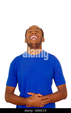 Homme portant un t-shirt bleu solide et permanent difficile de rire en tenant son estomac, white background studio Banque D'Images