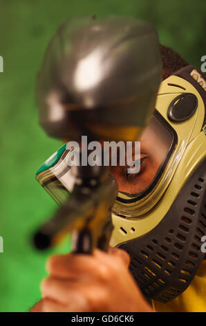 Portrait Gros plan homme portant vert et noir masque de protection paintball gun pointage caméra Banque D'Images