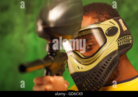 Portrait Gros plan homme portant vert et noir masque de protection paintball gun pointage caméra Banque D'Images