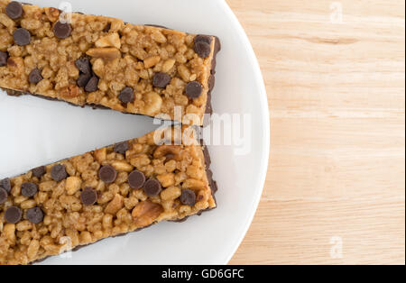 Haut de page Fermer la vue de deux éclats de chocolat avec des cacahuètes barres protéinées sur une plaque au-dessus d'une table en bois. Banque D'Images