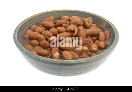 Une assiette de haricots écossés dans un vieux bol en grès isolé sur un fond blanc. Banque D'Images