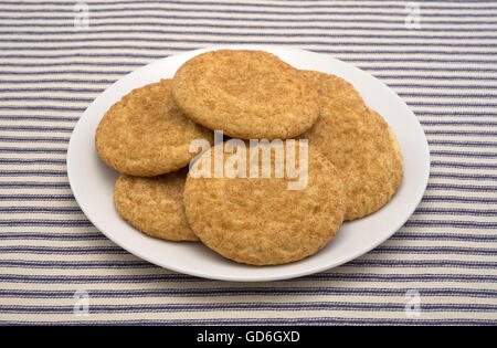 Vue de côté du the snickerdoodle cookies sur une plaque blanche au sommet d'une nappe à rayures bleu. Banque D'Images