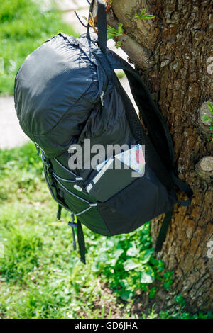 Sac à dos avec des équipements touristiques, libre. noir sac à dos avec la carte, portable et crayon accroché sur un arbre Banque D'Images