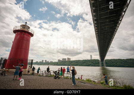 Les visiteurs de la Jeffrey's Hook Lighthouse, connu comme le 'Petit phare rouge' ci-dessous, le pont George Washington à New York lors de leurs portes ouvertes le dimanche, Juillet 10, 2016. Situé dans la région de Fort Washington Park, le phare a été construit en 1880 à l'origine de Sandy Hook, NJ et déplacé à Jeffrey's Hook en 1921. En 1931 lorsque le pont George Washington a été achevé le phare a été mis hors service, mais a été sauvé de la démolition par le biais de la demande publique a commencé par le livre pour enfants "Le Petit phare rouge et le grand pont gris', écrit par Hildegarde Swift et Lynd Ward en 1942. © Richard B. Banque D'Images