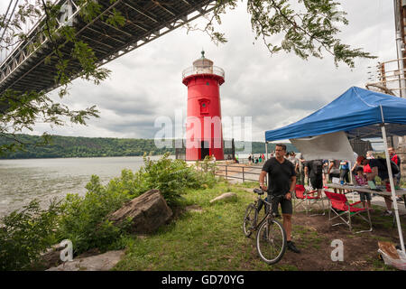 Les visiteurs de la Jeffrey's Hook Lighthouse, connu comme le 'Petit phare rouge' ci-dessous, le pont George Washington à New York lors de leurs portes ouvertes le dimanche, Juillet 10, 2016. Situé dans la région de Fort Washington Park, le phare a été construit en 1880 à l'origine de Sandy Hook, NJ et déplacé à Jeffrey's Hook en 1921. En 1931 lorsque le pont George Washington a été achevé le phare a été mis hors service, mais a été sauvé de la démolition par le biais de la demande publique a commencé par le livre pour enfants "Le Petit phare rouge et le grand pont gris', écrit par Hildegarde Swift et Lynd Ward en 1942. © Richard B. Banque D'Images