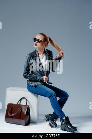 Fashion model sur white cube smiling dans lunettes de soleil Banque D'Images
