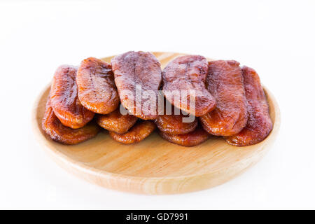 La Thaïlande dessert bananes séchées disposées sur une plaque de bois sur un fond blanc. Banque D'Images