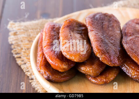 La Thaïlande dessert bananes séchées disposées sur une plaque de bois et toile sacs sur le plancher en bois. Banque D'Images