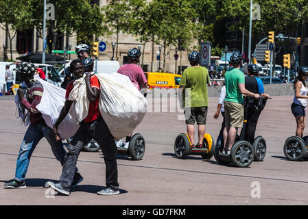 Deux vendeurs noirs transportant des marchandises dans un sac connu sous le nom de manteros entre touristes sur un segway dans le centre de Barcelone Banque D'Images