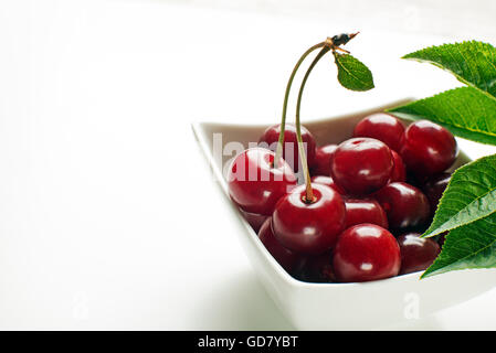 Dans un bol de cerises fraîches sur fond blanc close up Banque D'Images