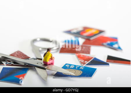 Carte de crédit de l'image concept dept une figure féminine assis avec une coupe de carte de crédit et d'une paire de ciseaux Banque D'Images