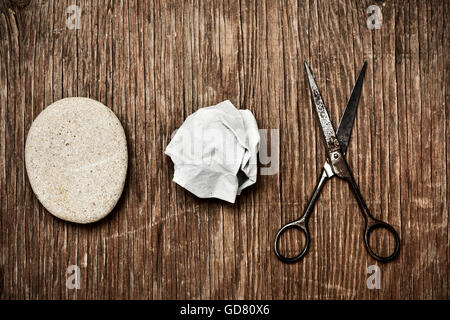 Capture d'un grand angle d'un rocher, un papier froissé et une vieille paire de ciseaux, illustrant la roche-papier-ciseaux jeu, on a rustic woo Banque D'Images