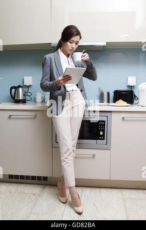 Les jeunes femmes utilisent des tablettes dans la cuisine Banque D'Images