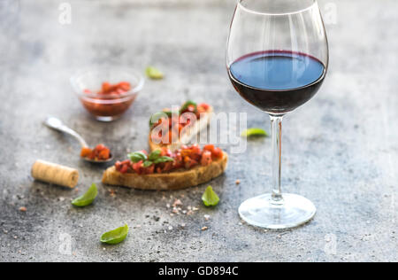 Verre de vin rouge et des canapés aux tomates et basilic, selective focus, composition horizontale Banque D'Images