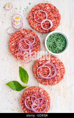 La viande de boeuf escalope pour faire des hamburgers avec oignons et épices blanc sur fond de bois, vue du dessus, la composition verticale Banque D'Images