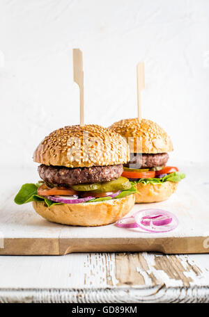 Deux des hamburgers faits maison servis avec des oignons sur sol en bois servant de sélection sur fond blanc, selective focus, vertical comp Banque D'Images