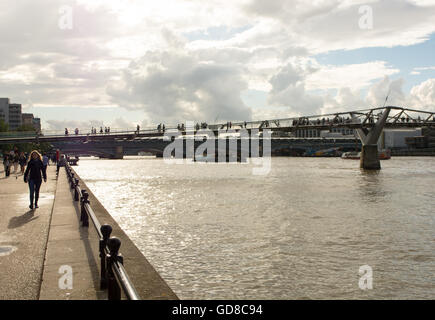 Plein soleil silhouettes de piétons sur le pont du millénaire sur la Tamise à Londres. Banque D'Images