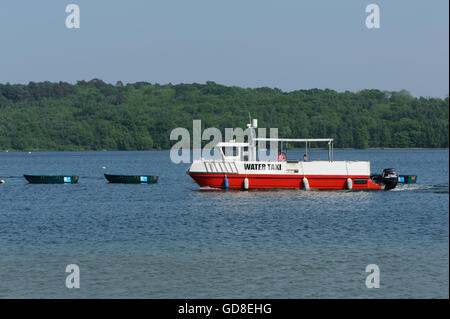 Un taxi d'eau passe à côté d'une rangée de barques amarrées. Bewl Water, Lamberhurst, Kent.UK Banque D'Images