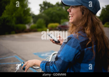 Fille rit à vos amis tout en jouant à Pokemon rendez de son vélo dans un parc local. Banque D'Images