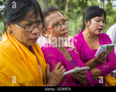 Ubud, Bali, Indonésie. Le 13 juillet, 2016. Femmes prient alors que le reste est incinérée au cours de la crémation de masse à Ubud. La population locale à Ubud exhumé les restes de membres de la famille et brûlé leurs reste dans une cérémonie de crémation de masse mercredi. Près de 100 personnes sera incinéré et reposent dans la plus grande masse la crémation à Bali en ans cette semaine. La plupart des gens sur Bali sont hindous. Crémations traditionnels de Bali sont très coûteux, afin que les collectivités habituellement une crémation de masse environ tous les cinq ans. Credit : ZUMA Press, Inc./Alamy Live News Banque D'Images