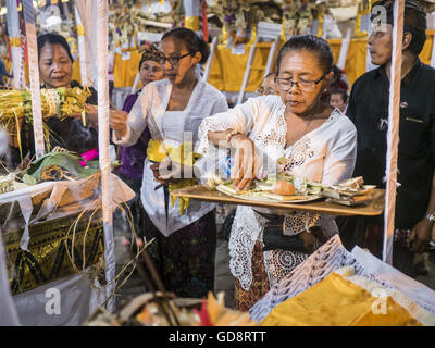 Ubud, Bali, Indonésie. Le 13 juillet, 2016. Les femmes bénisse les effigies de personnes incinérées dans la crémation de masse à Ubud mercredi. Les effigies, à son tour, être incinéré ce weekend. La population locale à Ubud exhumé les restes de membres de la famille et brûlé leurs reste dans une cérémonie de crémation de masse mercredi. Près de 100 personnes sera incinéré et reposent dans la plus grande masse la crémation à Bali en ans cette semaine. La plupart des gens sur Bali sont hindous. Credit : ZUMA Press, Inc./Alamy Live News Banque D'Images