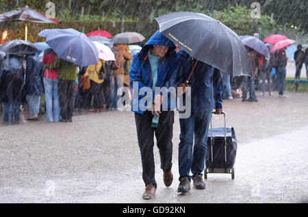 Hanovre, Allemagne. Le 13 juillet, 2016. Les visiteurs avec des parasols se tenir dans les jardins de Herrenhausen à la première de 'Kleines Fest im Grossen Garten" à Hanovre, Allemagne, 13 juillet 2016. Un orage avec des éclairs et tonnerre, pluie et tempête a provoqué la fin de la première soirée des arts festival. Photo : Julian Stratenschulte/dpa/Alamy Live News Banque D'Images