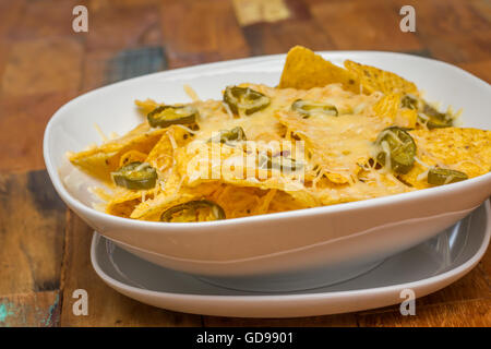 Nachos au fromage avec du fromage et les jalapenos dans un bol blanc Banque D'Images