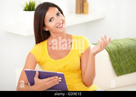 Carefree woman holding a tablet avec une main posée en regardant la caméra Banque D'Images