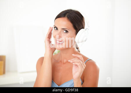 Jolie femme latine smiling while listening to music on headphones à piscine Banque D'Images