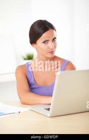Jolie femme hispanique en violet t-shirt à pissé pendant l'utilisation de l'ordinateur au travail Banque D'Images