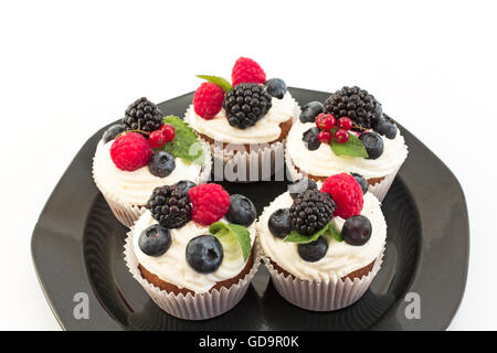 Cupcakes aux fruits rouges élégants sur la plaque noire. Banque D'Images