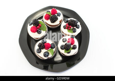 Cupcakes aux fruits rouges élégants sur la plaque noire. Banque D'Images