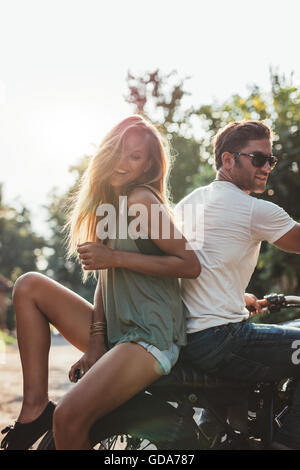 Jeune couple assis sur une moto et avoir du plaisir. Jeune homme et femme sur la moto. Banque D'Images