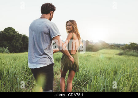 Jeune couple la marche à l'extérieur le long chemin à travers champ pays de l'herbe. L'homme et la femme se promenant dans un pré, profitant de vacances dans le NAT Banque D'Images