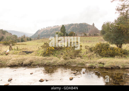 L'Irlande, le comté de Wicklow, rivière à Glendalough (vallée des deux lacs) est une vallée dans les montagnes de Wicklow en Irlande. Monastère avec tour ronde Banque D'Images