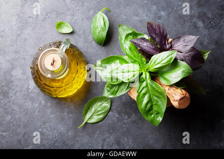 Jardin des herbes fraîches de basilic dans du mortier et d'huile d'olive sur table en pierre. Vue d'en haut Banque D'Images