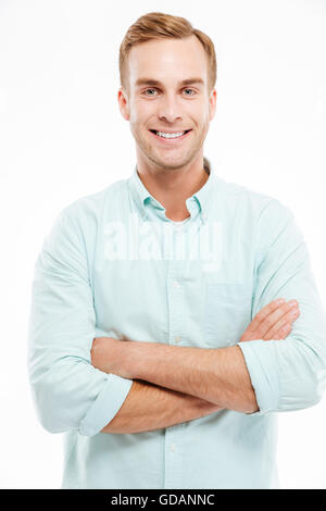 Portrait of a happy casual man standing with arms folded over white background and looking at camera Banque D'Images