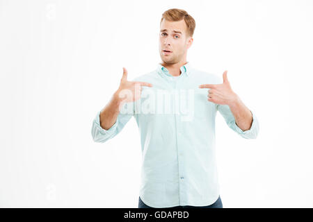 Surpris handsome young man et en pointant sur lui-même sur fond blanc Banque D'Images