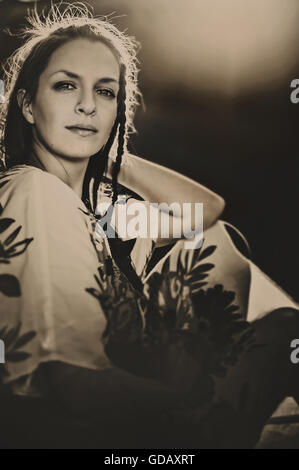 Portrait de la belle jeune femme assise dans la nature par l'arbre Banque D'Images