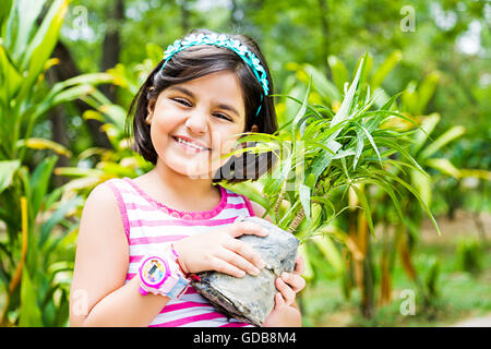 1 Indian Kid girl park holding Potted Plant Banque D'Images