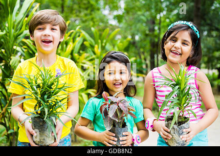 Les enfants indiens 3 Amis park holding Potted Plant Banque D'Images