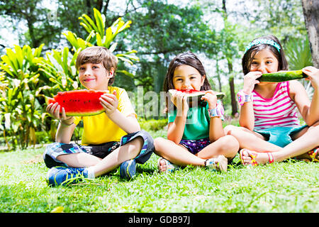 Les enfants indiens 3 amis park Eating Watermelon fruits Banque D'Images