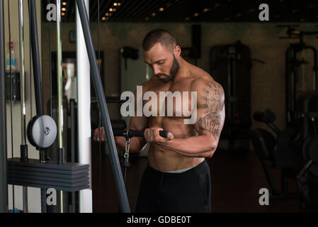Big Tattooed Man dans le sport est l'exercice de biceps sur la Machine - Modèle musculaire Bodybuilder athlétique dans l'exercice au centre de remise en forme Banque D'Images