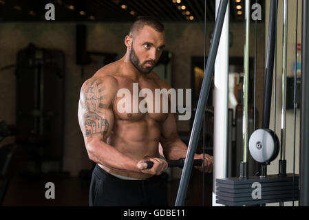 Big Tattooed Man dans le sport est l'exercice de biceps sur la Machine - Modèle musculaire Bodybuilder athlétique dans l'exercice au centre de remise en forme Banque D'Images