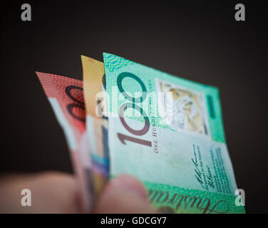 Une main tenant un 20,50 et 100 Australian dollar notes sur un fond noir Banque D'Images