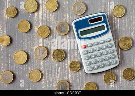 Calculatrice et pièces en euro sur fond de bois gris Banque D'Images