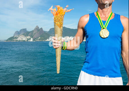 Médaille d'or de l'athlète brésilien avec torche sport permanent au-dessus de Rio de Janeiro Brésil skyline at Ipanema Beach Banque D'Images