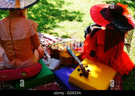 Deux femmes et violoncelle. femmes dans le parc sur l'herbe se reposant après le concert. Banque D'Images