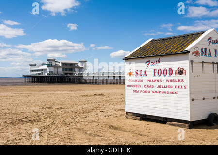 Un étal de fruits de mer sur la plage de Weston-super-Mare avec le Grand Pier derrière, North Somerset, Angleterre. Banque D'Images